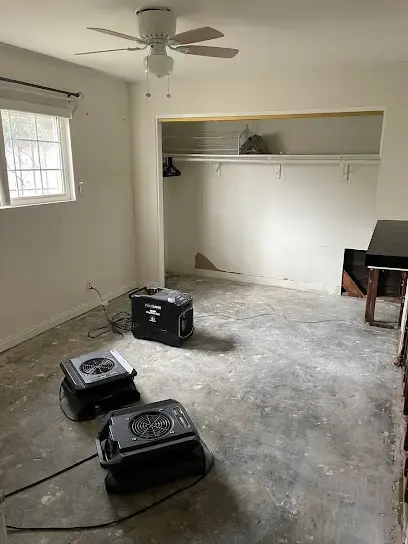 Dehumidifiers and air movers drying a bedroom slab after flooring removal in El Monte