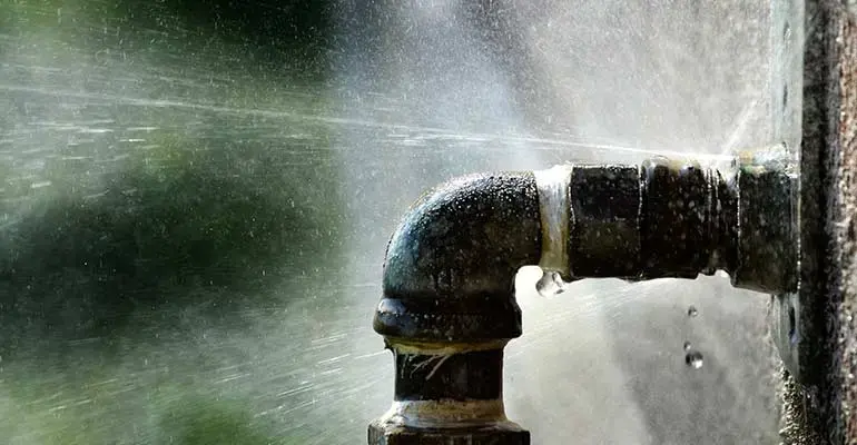 Water spraying from a split iron pipe fitting in El Monte