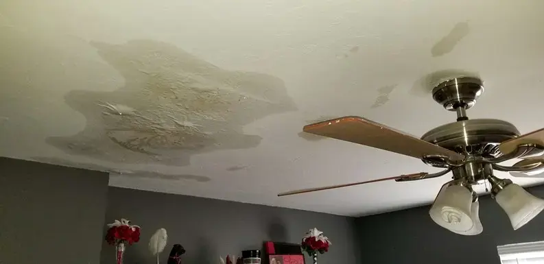Water stain spreading across a living room ceiling beside a fan in El Monte